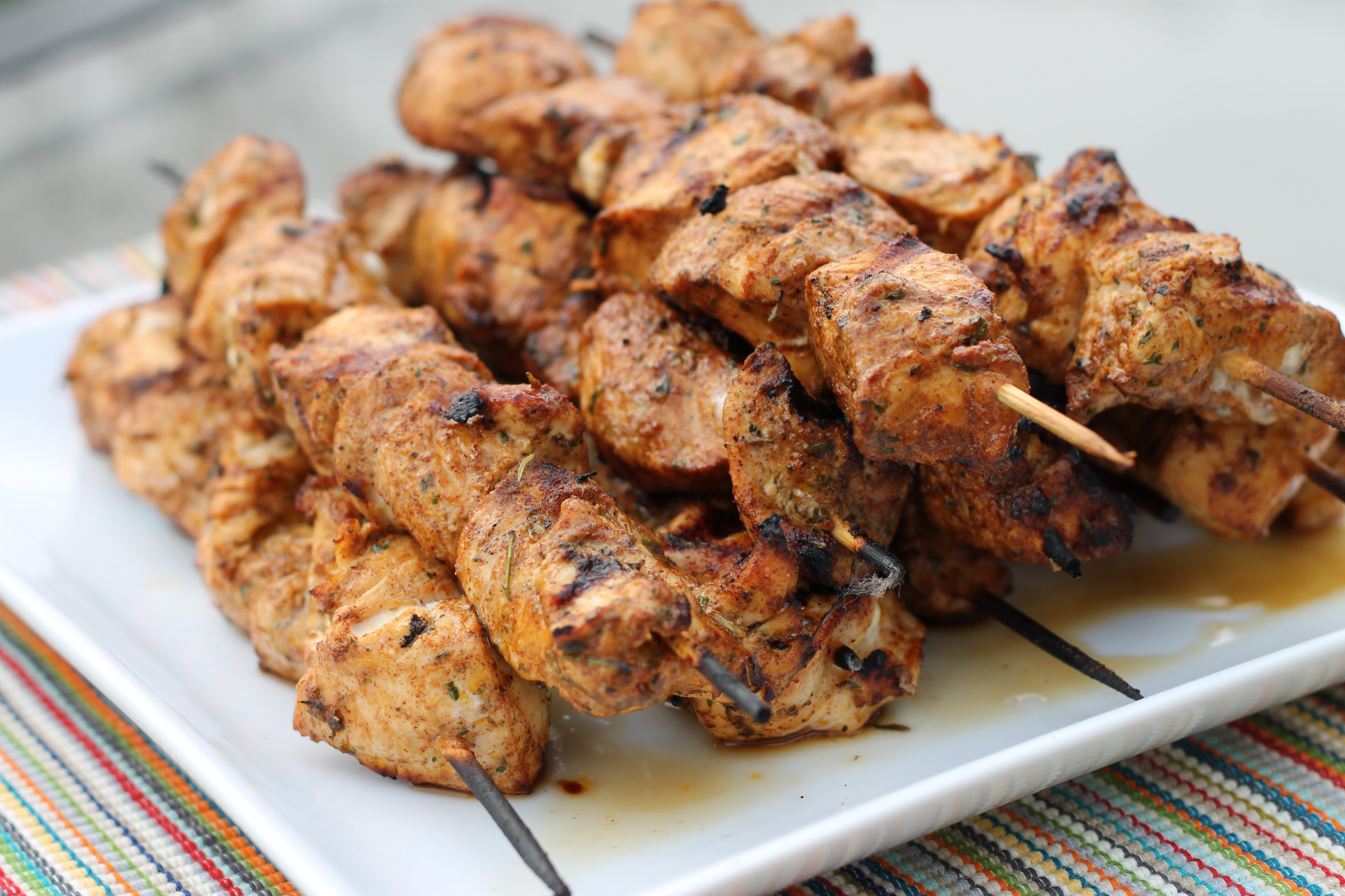 Southwest Grilled Chicken Kabobs stacked up on a square white platter.