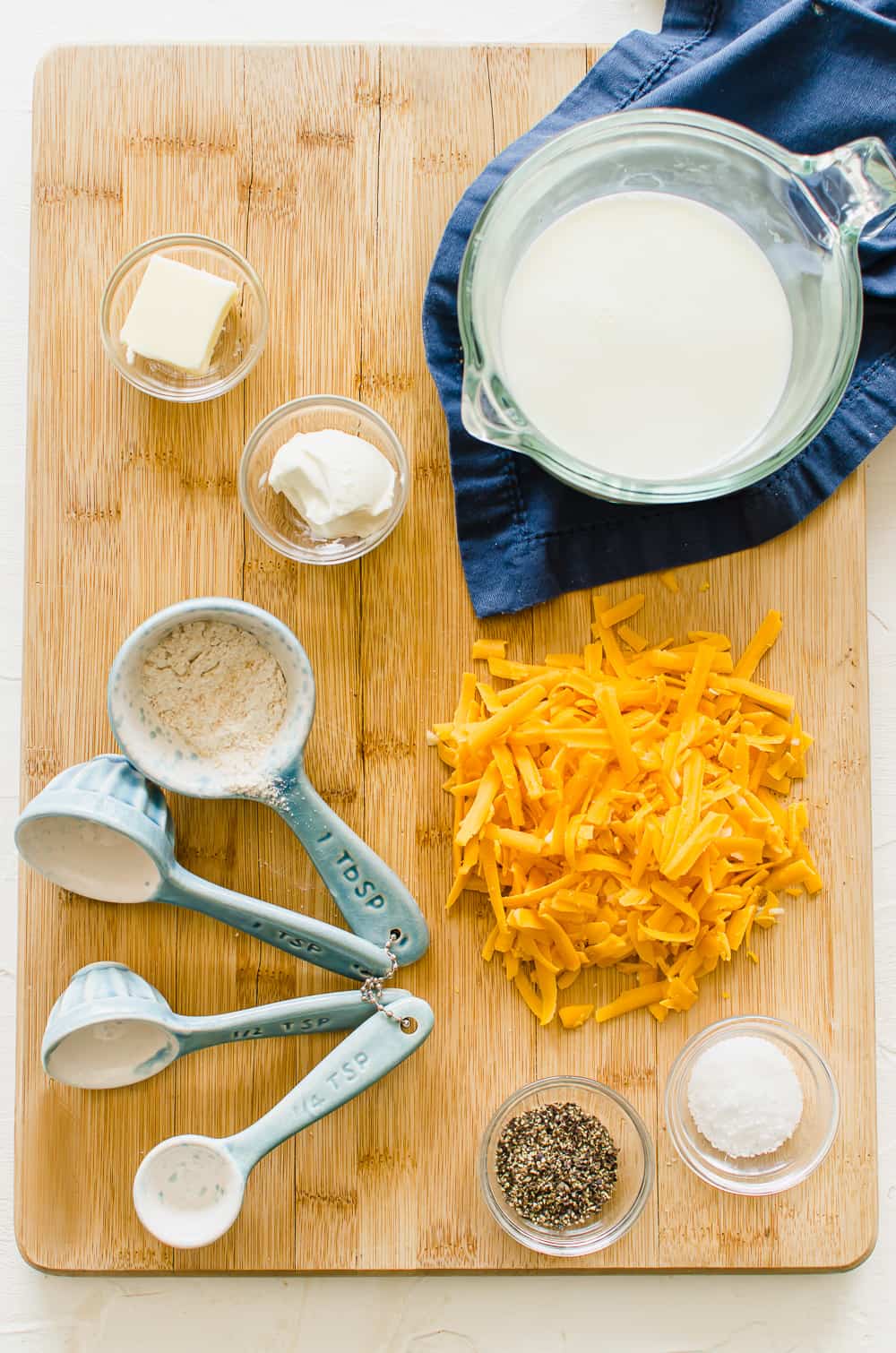 ingredients for cheese sauce on a wooden cutting board