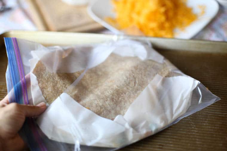 Tortillas separated by parchment paper in a freezer bag.