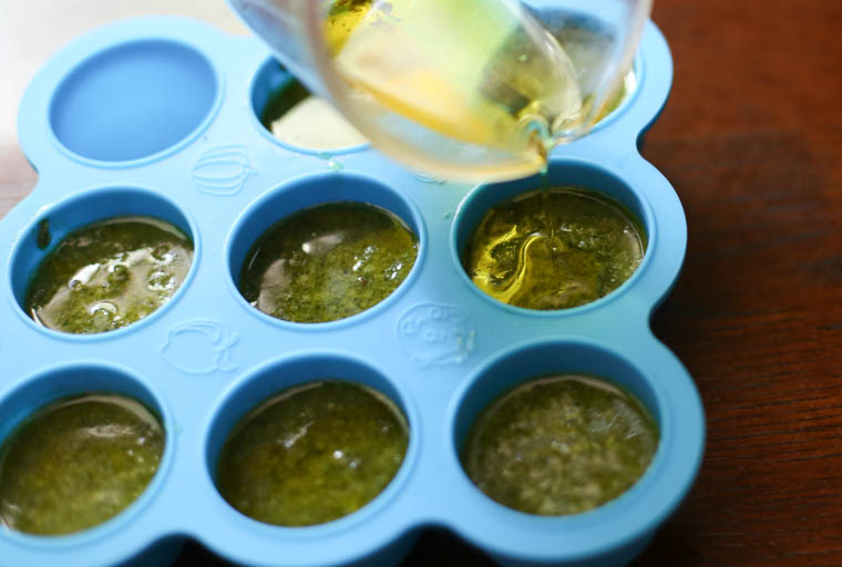 pouring olive oil over pesto to prep for freezing 