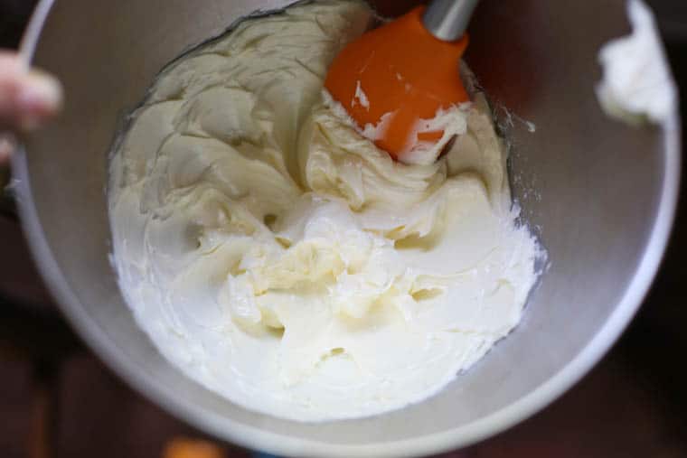 Softened butter being whipped up to make garlic herb butter.