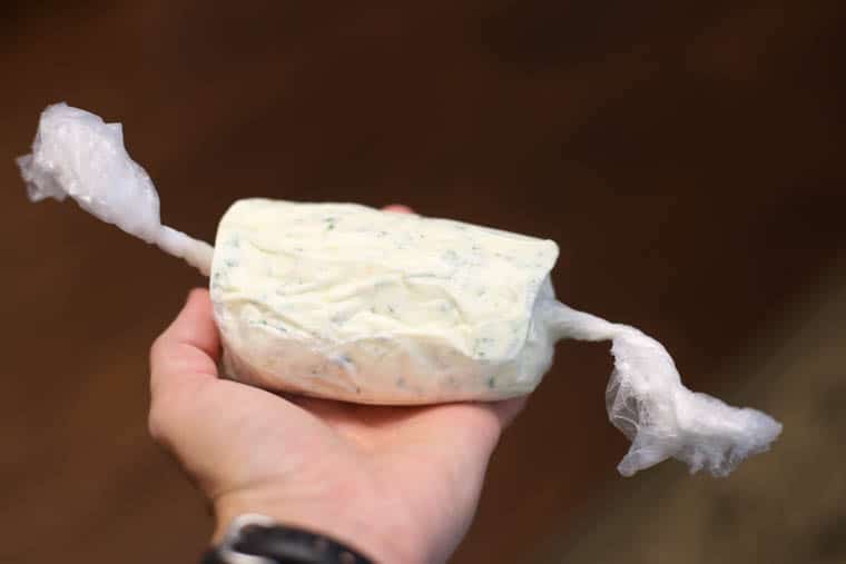 Garlic herb butter formed, wrapped with plastic wrap, and ready for the fridge.