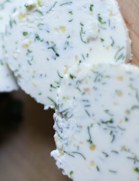 Slices of garlic herb butter on a cutting board.