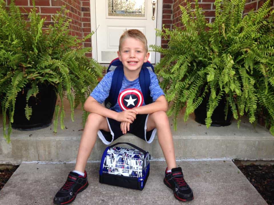 A boy with a backpack and lunch box.