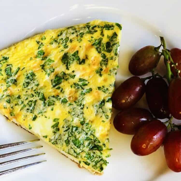 Spinach cheese frittata on a plate with grapes.