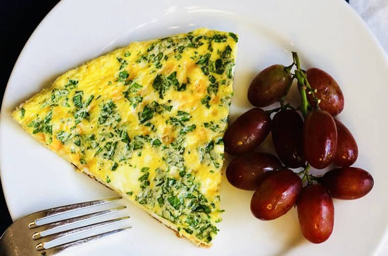 spinach cheese frittata on a plate with grapes.