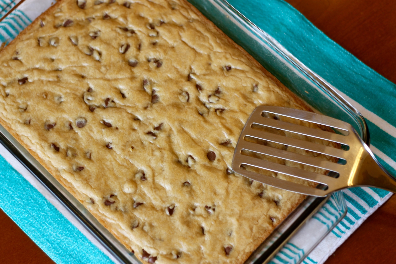 Overhead shot of chocolate chip blondies in a glass pan with spatula