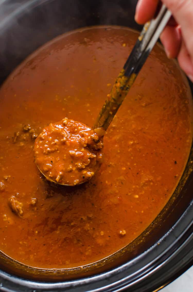 Spaghetti sauce being ladled out of a slow cooker.