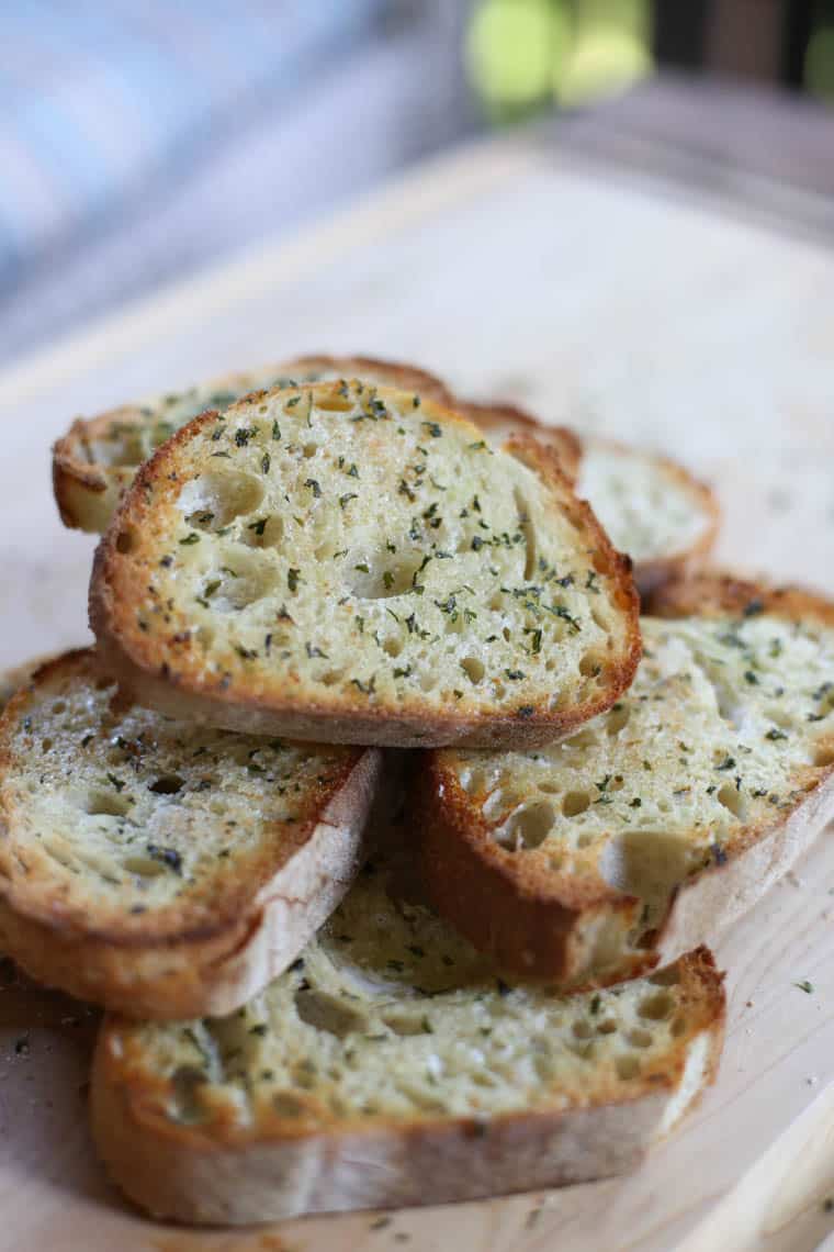 Texas toast stacked up on a wooden cutting board.