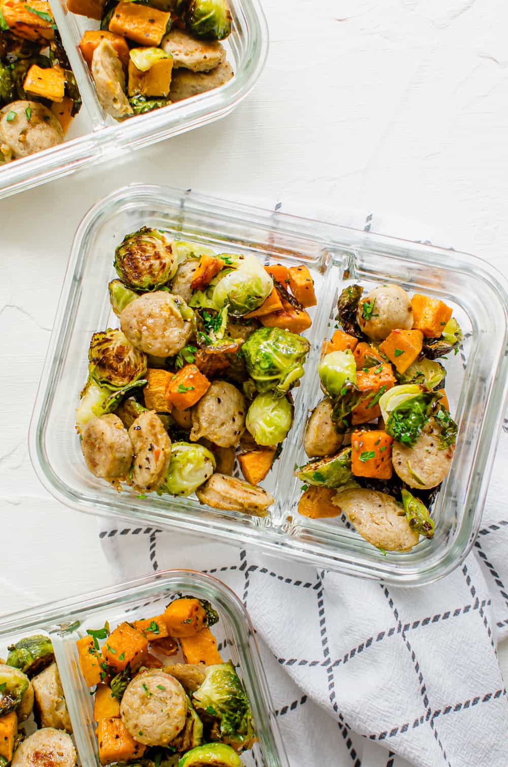 roasted chicken sausage, Brussels sprouts, and sweet potatoes in a glass meal prep dish.