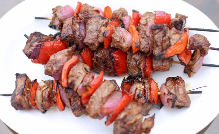 Grilled sirloin steak kabobs on a platter.