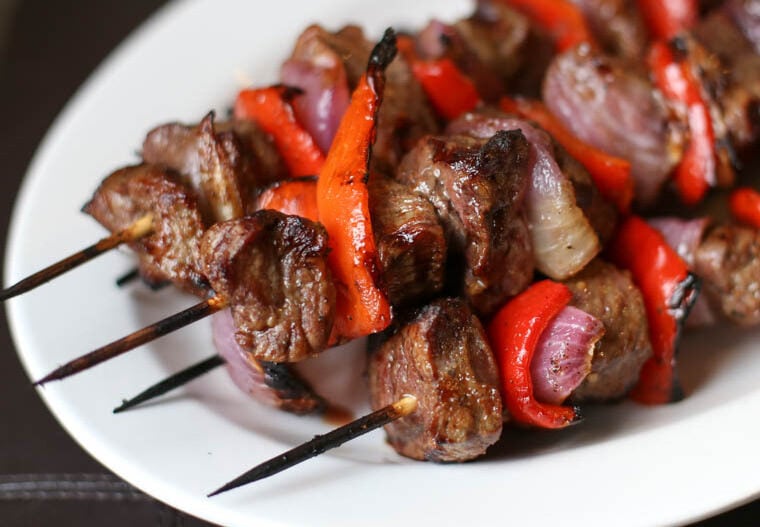 close up shot of grilled steak kabobs with bell peppers and red onions on a plate