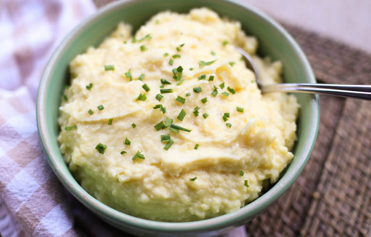 A bowl of Instant Pot Mashed Potatoes with chopped chives on top. 