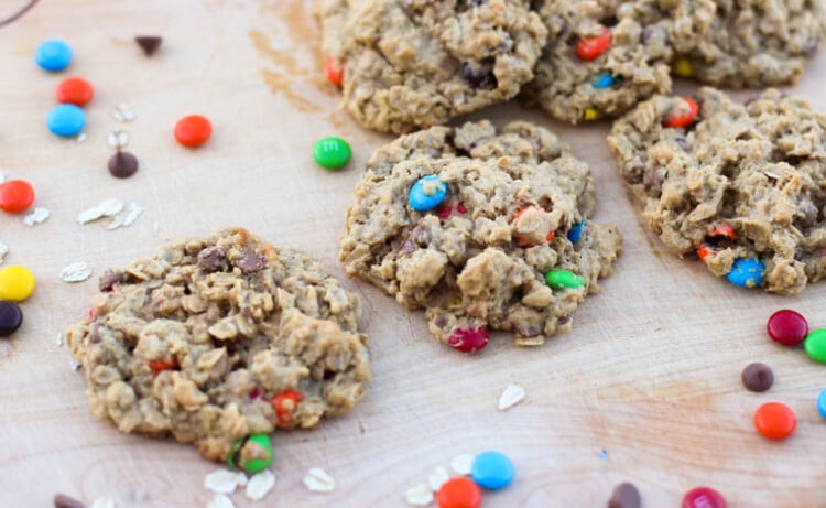 Monster cookies on parchment paper with M&M's sprinkled around them.