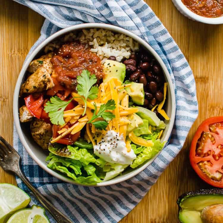 Chicken burrito bowl with fresh cilantro, diced avocado, and a dollop of sour cream on top.