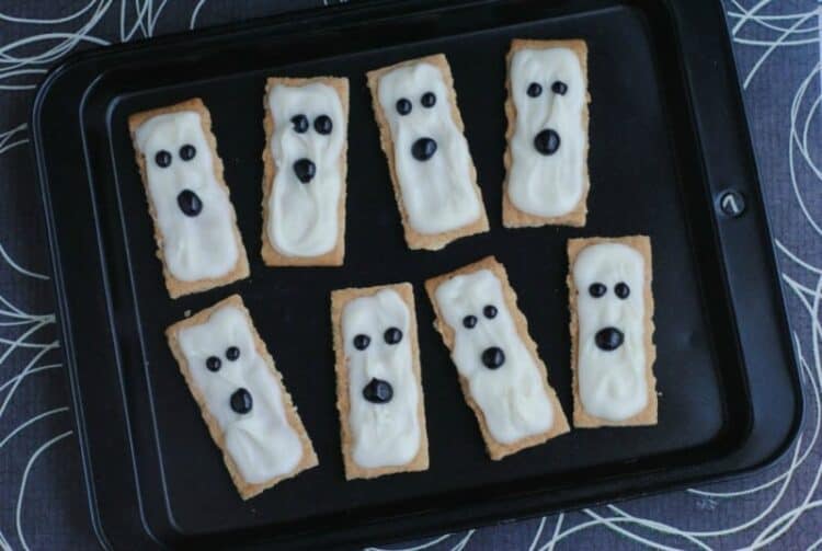 Graham crackers covered in white icing with black eyes and a mouth to look like ghosts.