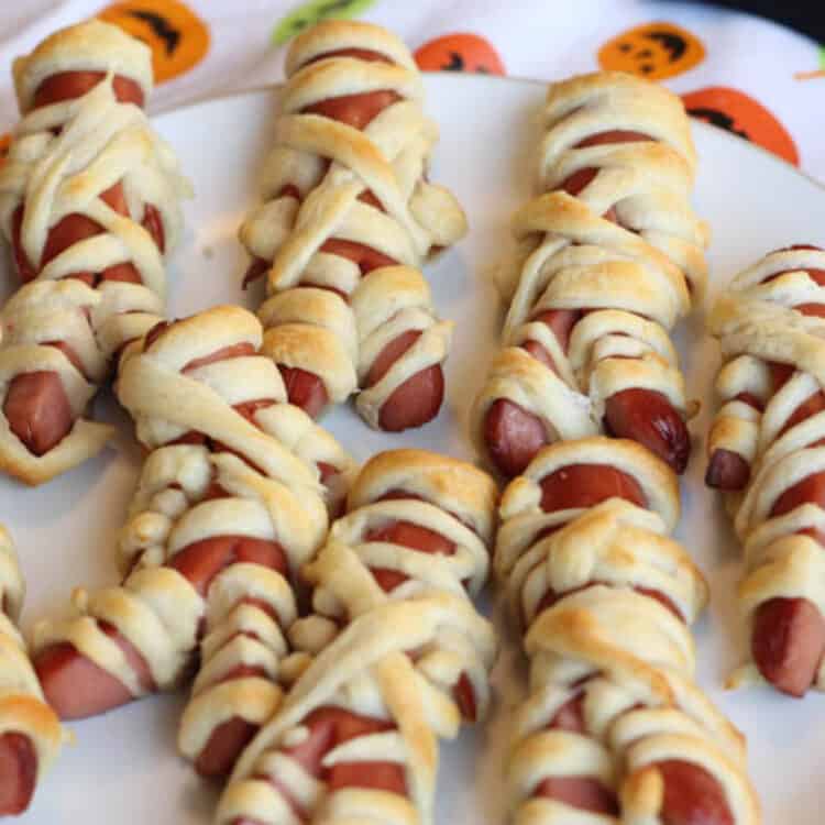 Mummy hot dogs being served on a white plate.