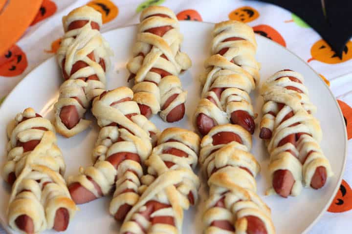 Mummy hot dogs being served on a white plate.