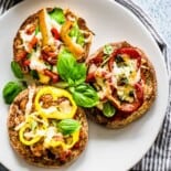 English muffin pizzas being served on a white plate.