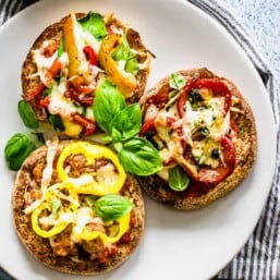 English muffin pizzas being served on a white plate.