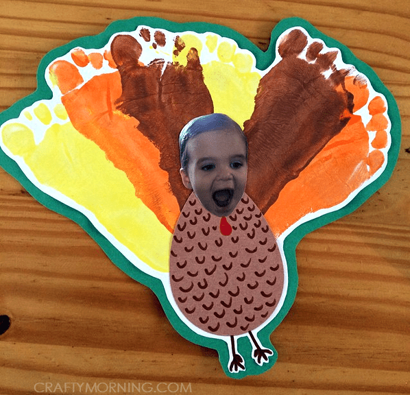 Different color child footprints as feathers for a turkey with the head a cutout of the child's face.