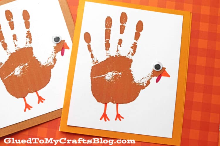 A card made out of gold and white card stock with a brown hand print on the front decorated to look like a turkey.