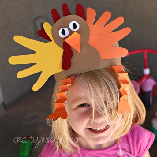 Young girl with a construction paper hat made to look like a turkey.