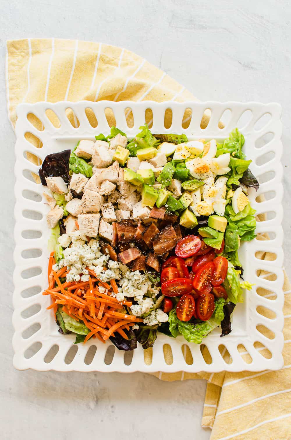 cobb salad on a white plate with yellow napkin