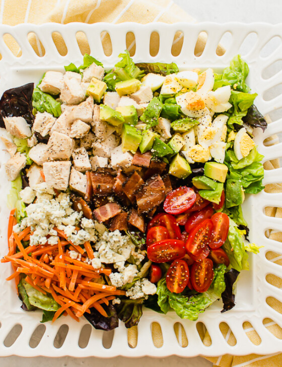 cobb salad on a white plate with yellow napkin