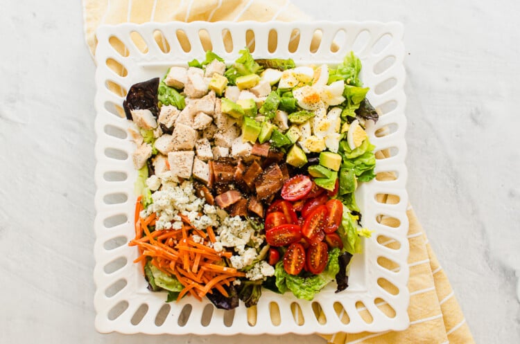 A cobb salad on a square white plate.