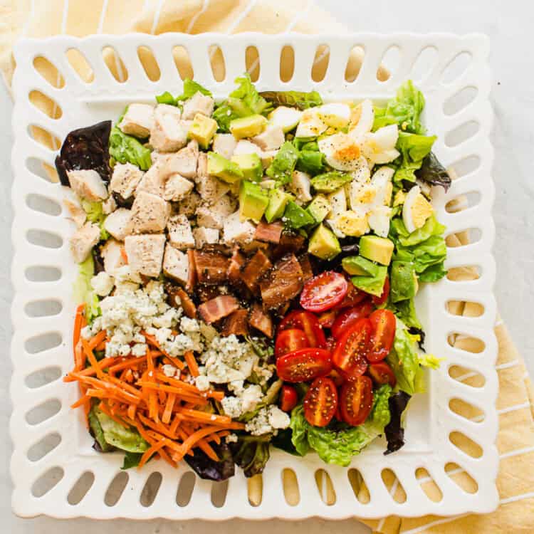 A cobb salad on a square white plate.