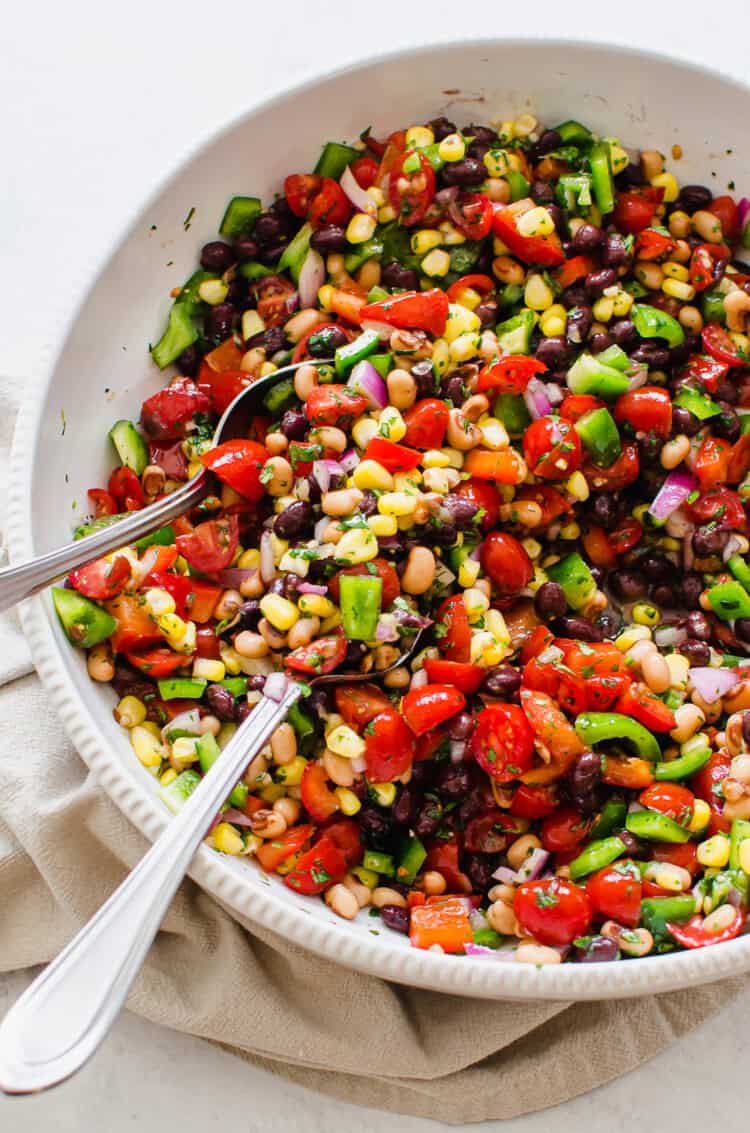 Fiesta salad in a white bowl with serving spoons.