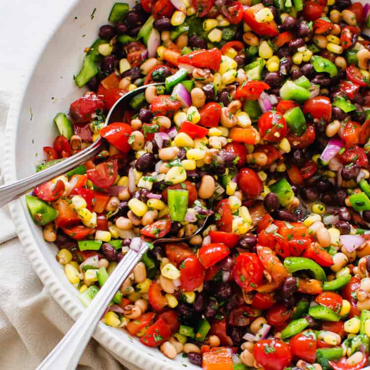 Fiesta salad in a white bowl with serving spoons.