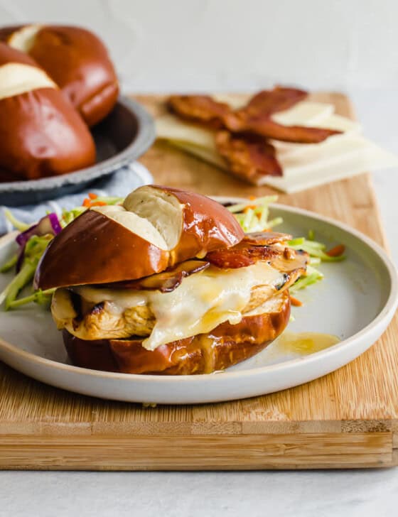 Honey Dijon chicken cutlet on a pretzel bun with cheese, lettuce, and bacon.