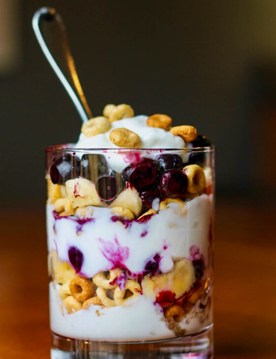 Breakfast Cereal Parfait in a glass with layers of Greek yogurt, blueberries, and Cheerios.