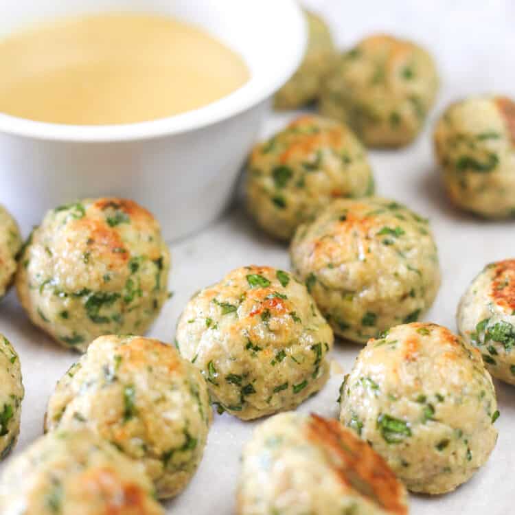 Chicken meatballs on a pan with honey mustard dipping sauce.