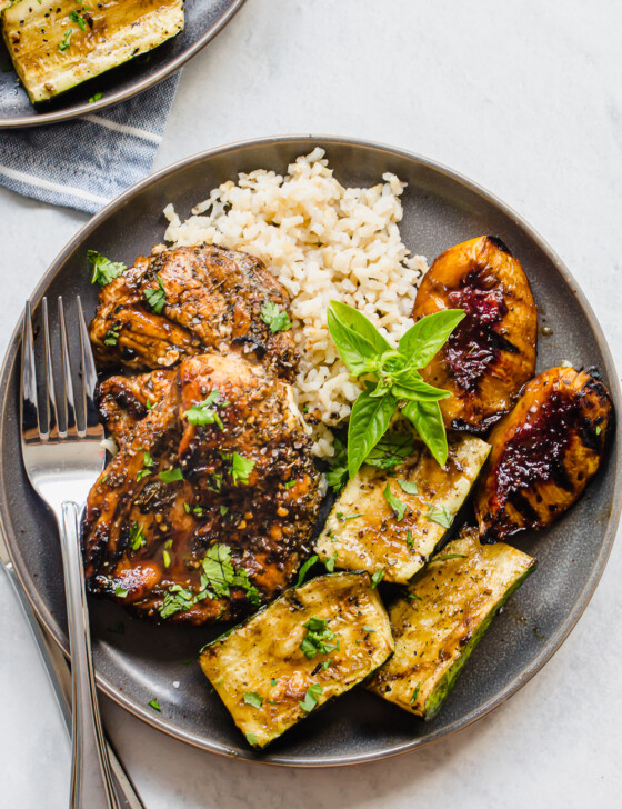 grilled chicken, rice, zucchini, and peaches on a gray plate with fork