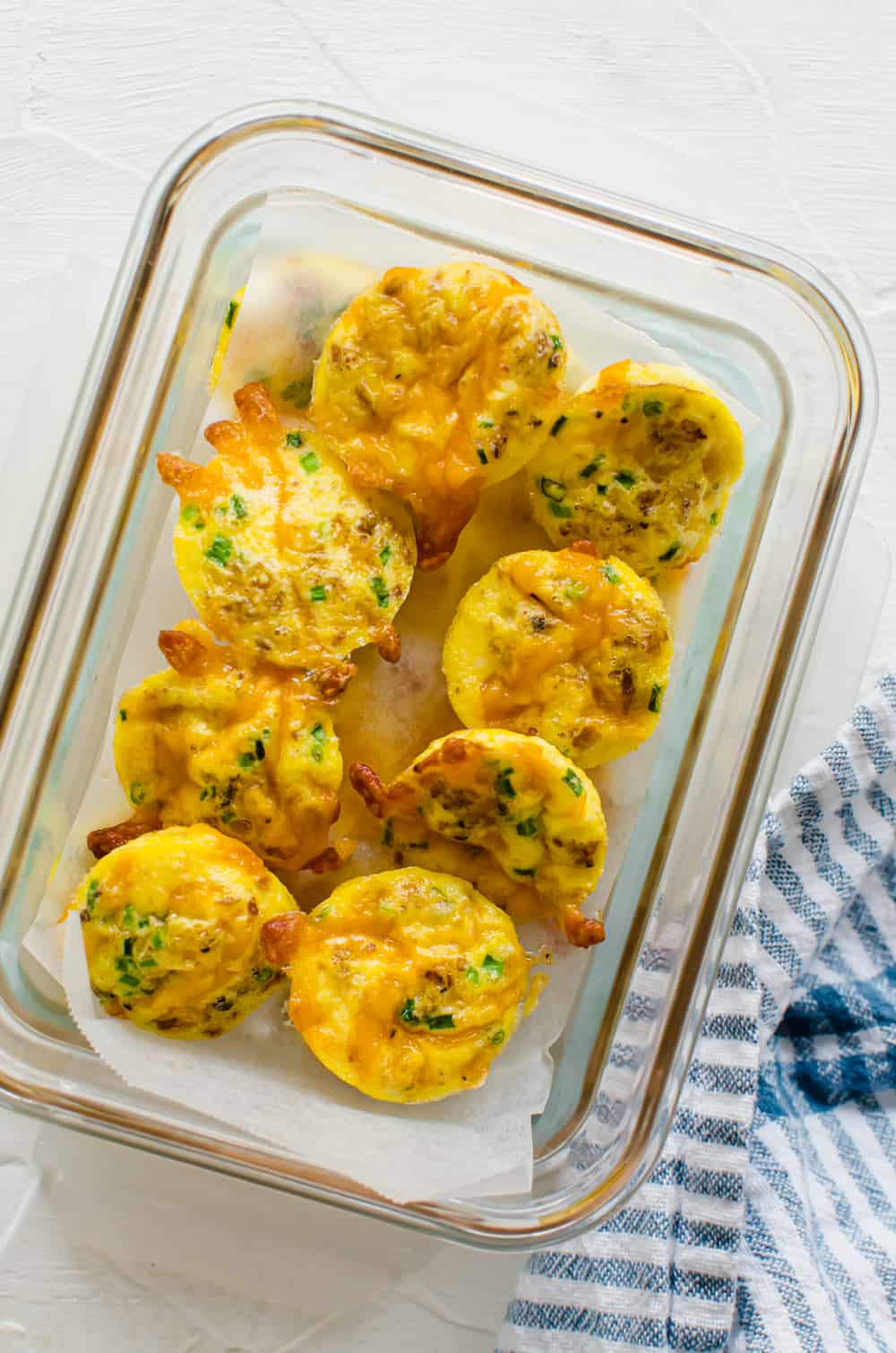 Mini egg bites in a freezer storage container with parchment paper.