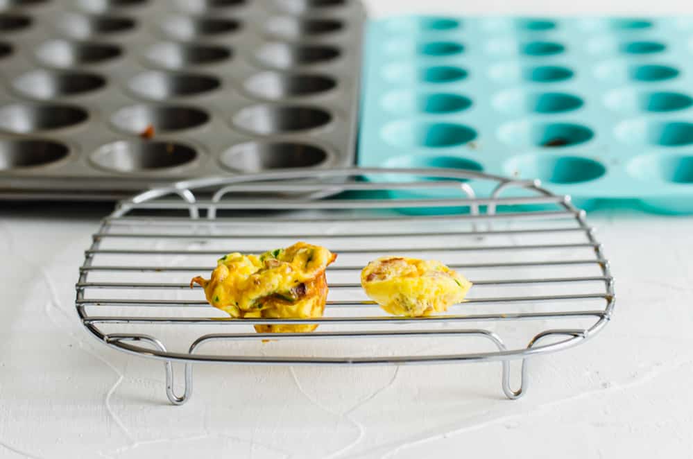two egg bites on a cooling rack to demonstrate the difference between one made in a metal pan and one in a silicone pan