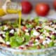 Autumn Salad in a glass bowl with Apple Cider Vinaigrette being poured on top.