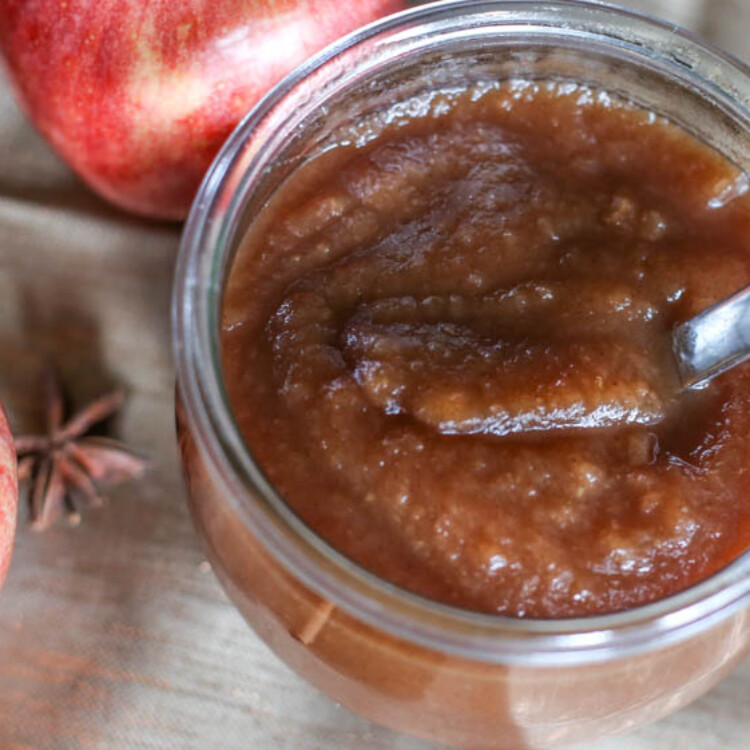 A jar of apple butter with a spoon in it.