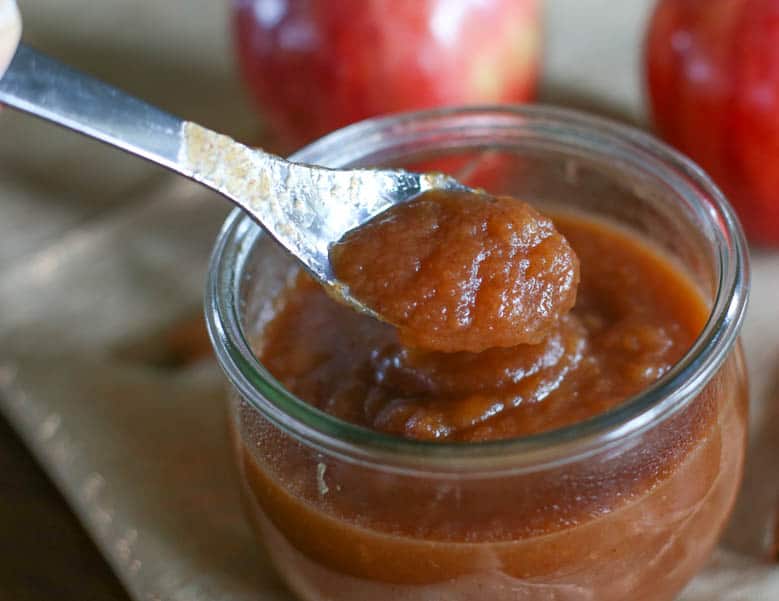 Homemade apple butter in a small jar with a spoon scooping some out.