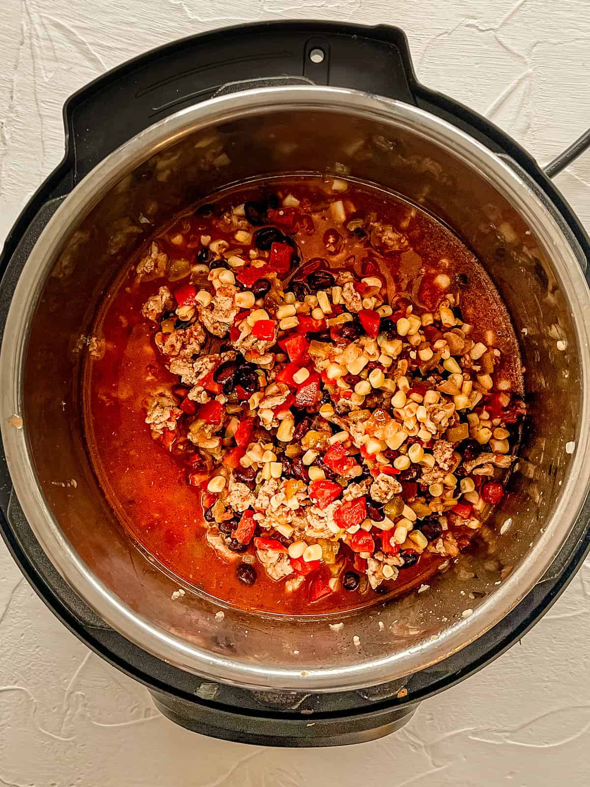 Taco soup ingredients in the instant pot ready to be cooked.