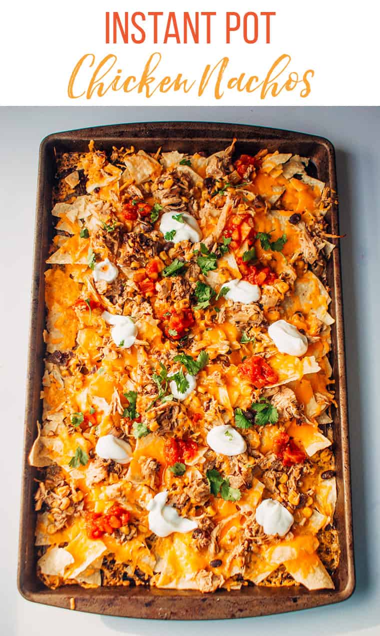 Freezer-friendly Instant Pot chicken nachos on a baking sheet with dollops of sour cream on top.