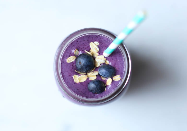 overhead shot of a blueberry smoothie in mason jar with straw