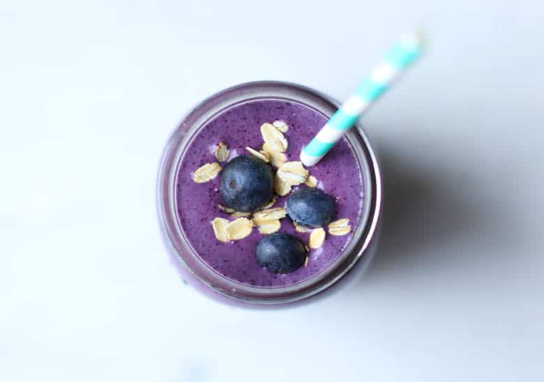 Looking into the top of a mason jar of blueberry smoothie with blueberries and oats on top.