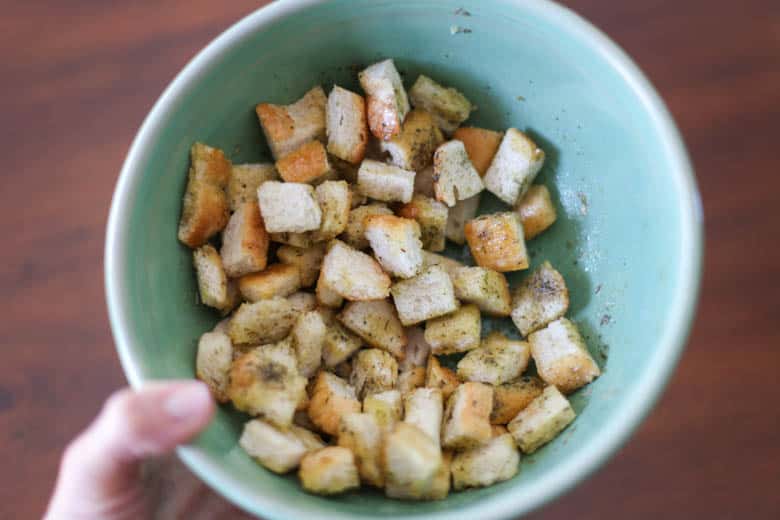 Seasoned bread pieces in a green bowl to be made into homemade croutons.