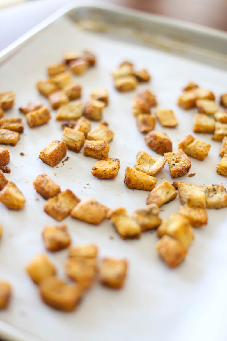 Homemade croutons on a parchment-lined baking sheet just out of the oven.
