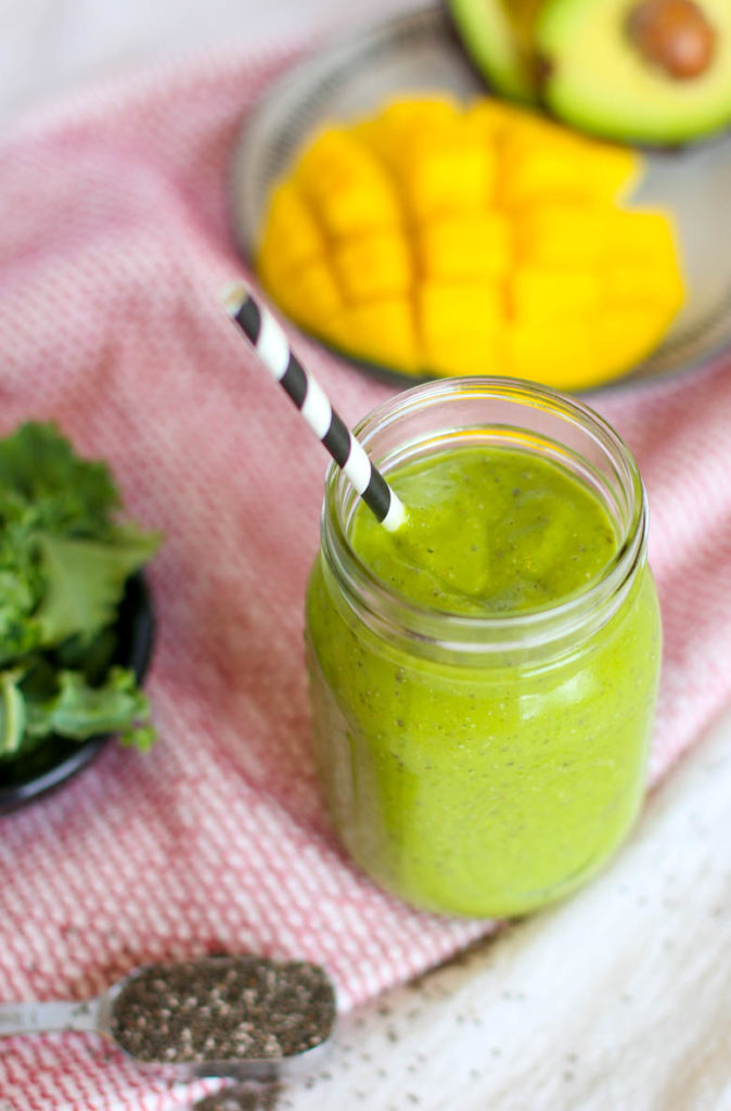 green machine smoothie with mango and chia in mason jar with straw