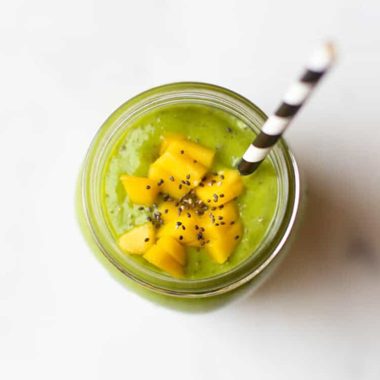 Looking into the top of a mason jar of green machine smoothie with mango chunks and chia seeds on top.